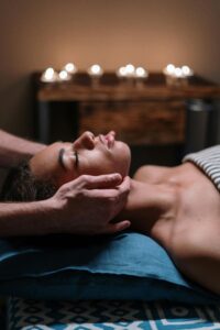 Woman receiving a calming facial massage in a tranquil spa setting with candlelight.